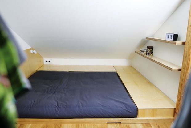 Nízké postele mají netypický odkladní a úložný prostor pod zešikmenou střechou. Foto TRAGA
