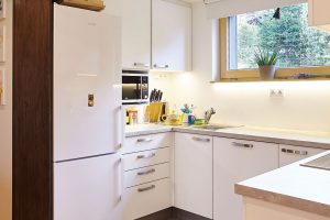 Minimalisticky řešená kuchyň navazuje na hlavní obytnou místnost. Oba prostory opticky odděluje snížený podhled a kontrast materiálů. FOTO: Jiří Princ