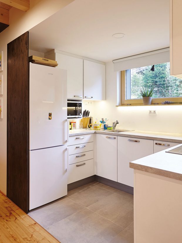 Minimalisticky řešená kuchyň navazuje na hlavní obytnou místnost. Oba prostory opticky odděluje snížený podhled a kontrast materiálů. FOTO: Jiří Princ