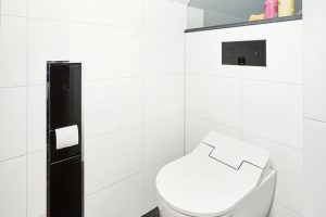 Investor si přál, aby se i zařízení koupelny přizpůsobilo bílo-černé barevné kombinaci, která je příznačná pro celý interiér rodinného domu. Ta se objevuje i v prostoru toalety, kde se nachází černé splachovací WC tlačítko vsazené do bílého obkladu. FOTO VIEGA, ROSE BENNINGHOFF