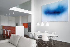 Interiéru dominuje bílá barva, kontrastní jsou pouze oranžové plochy na kuchyňské lince a modrý obraz. FOTO FILIP ŠLAPAL
