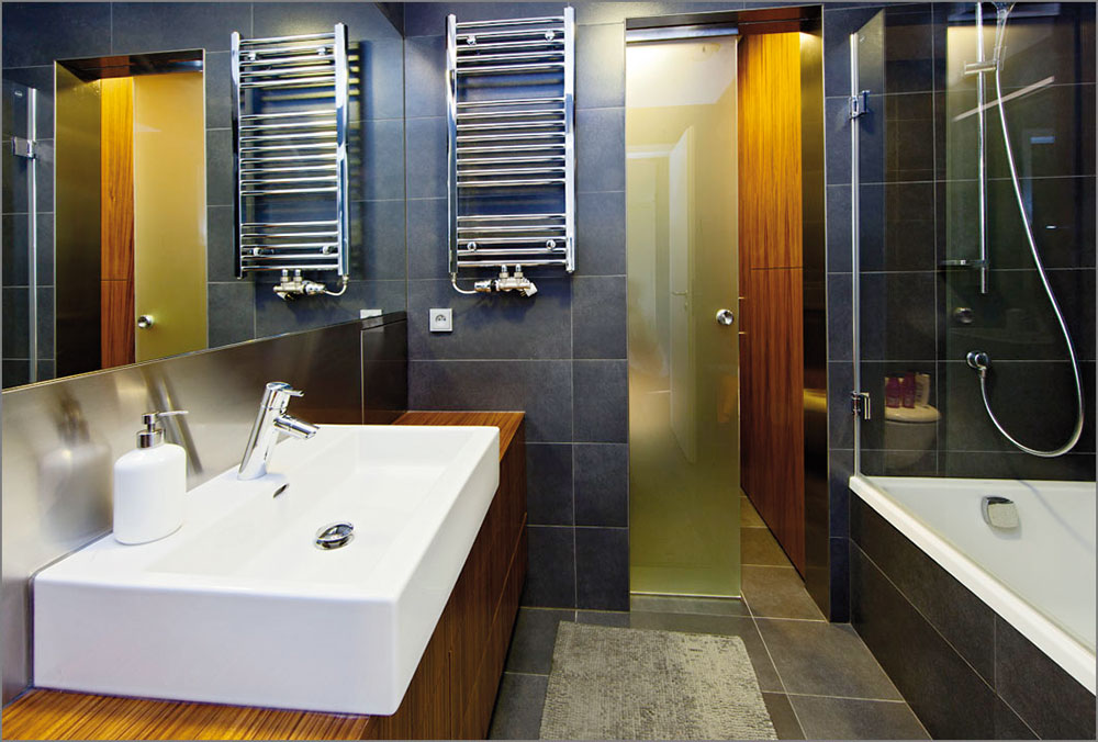 Dřevo v kombinaci s bílou a šedou barvou se objevuje i v koupelně. Větší obdélníkové obklady pokrývají stěny i podlahu. FOTO FOTES, JIŘÍ VANĚK