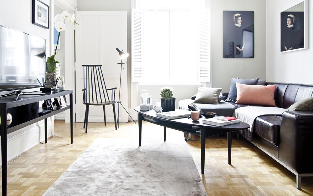 Obývací pokoj je úsporně zařízen. Velkou koženou pohovku doplňuje pouze elegantní kávový stolek, subtilní křeslo J110 od značky Hay a televizní konzolová skříňka.FOTO WESTWING