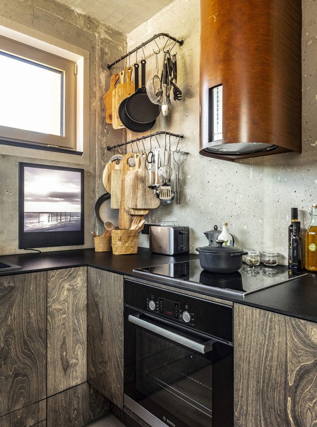 Kuchyně je vyvedena ve dřevě s výraznou kresbou. Uzavřené skříňky doplňují držáky z roxorových tyčí na kuchyňské náčiní. FOTO JH STUDIO