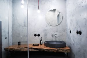 V bytě jsou dvě naprosto odlišně pojaté koupelny. V jedné je použita betonové stěrka a umyvadlová deska z výrazného kusu exotického dřeva... FOTO ZDENĚK BUCHLÁK
