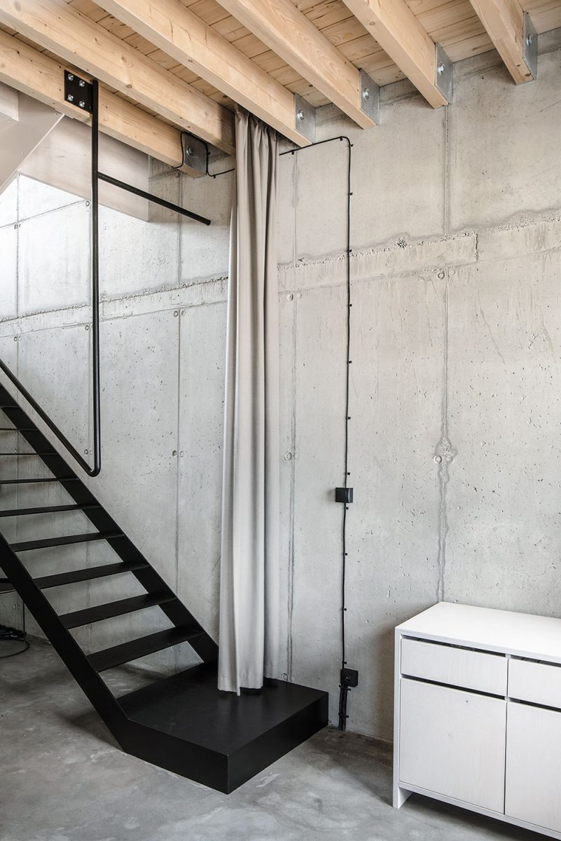 Otevřený prostor bytu má několik úrovní. Černé ocelové schodiště spojuje vstupní podlaží a obývací pokoj umístěný o patro výš. Podlahu tvoří dřevěná konstrukce vsazená do betonového obalu. FOTO LOUSY AUBER