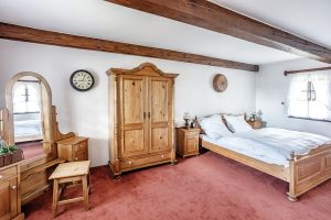 Ložnice se chlubí nejen krásnou dřevěnou postelí s vyřezávaným čelem, ale i toaletním stolkem a robustní šatní skříní. FOTO JIŘÍ HURT