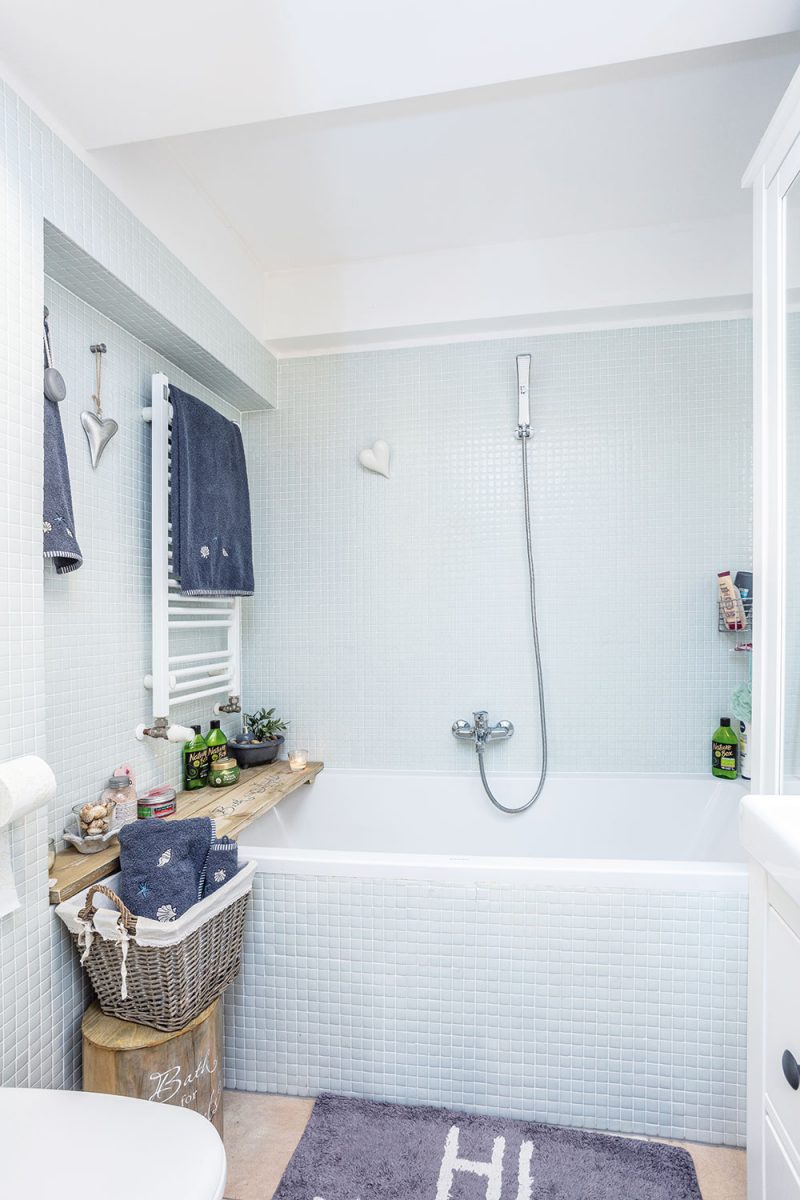 Koupelna je obložená bílým mozaikovým obkladem a doplněná dřevěnými a proutěnými prvky. FOTO JIŘÍ HURT