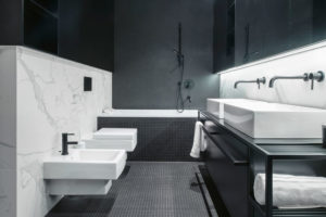 V koupelně taktéž dominuje kontrast černé a bílé barvy, kterou opticky zjemňuje použití mramoru.