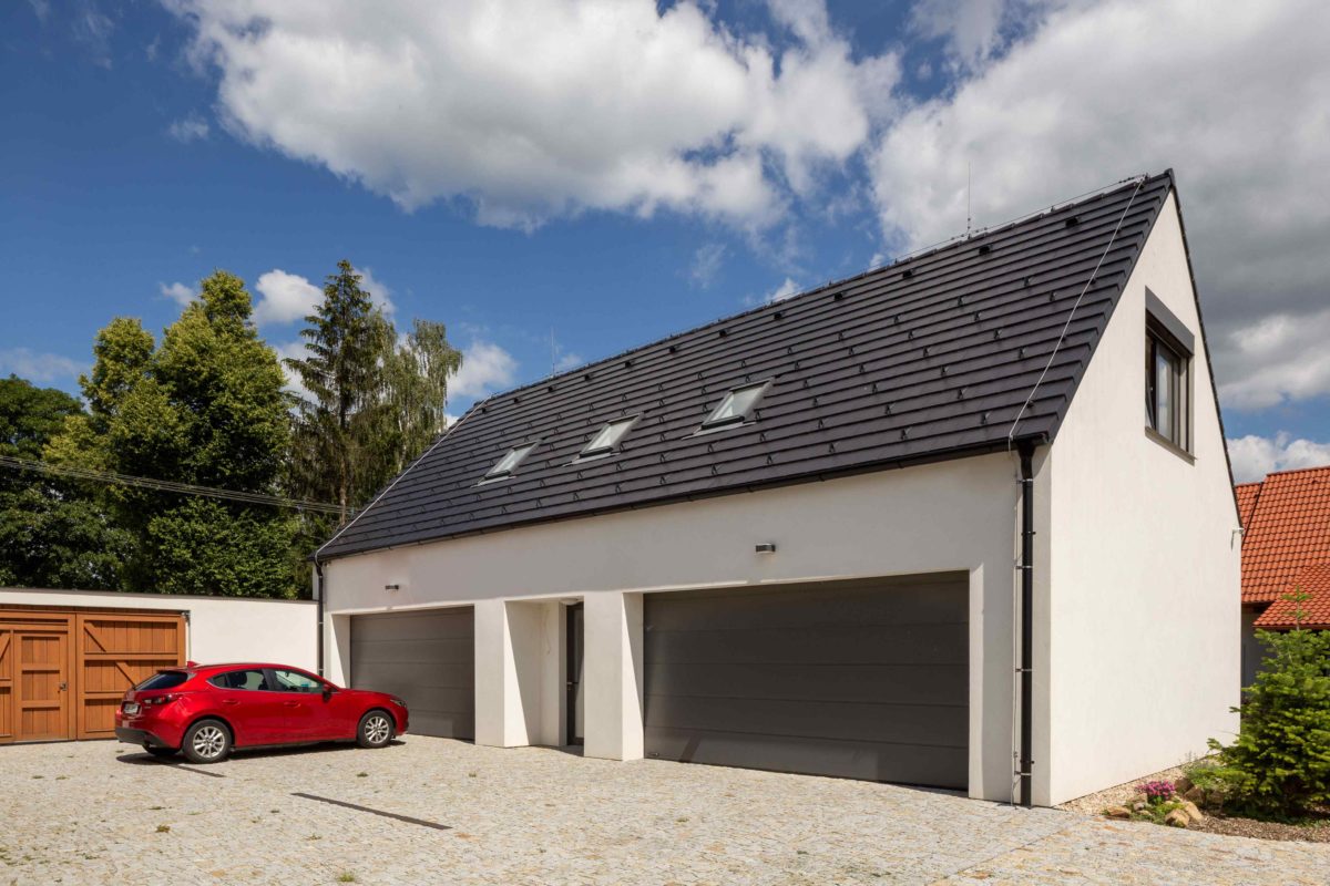 Bílá garáž s antracitovou střechou a rudým autem