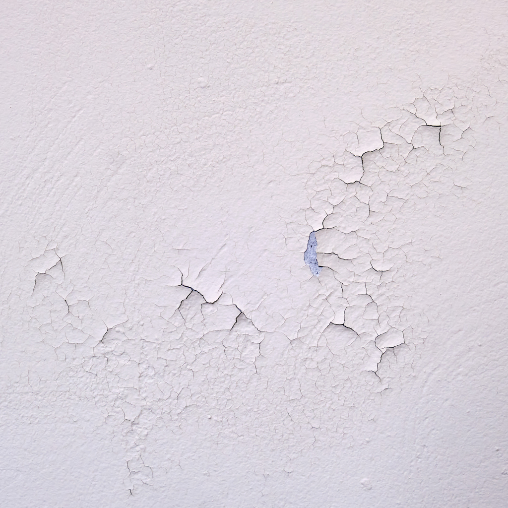Spoiled fresh white paint close-up. Cracked new paint on a white wall