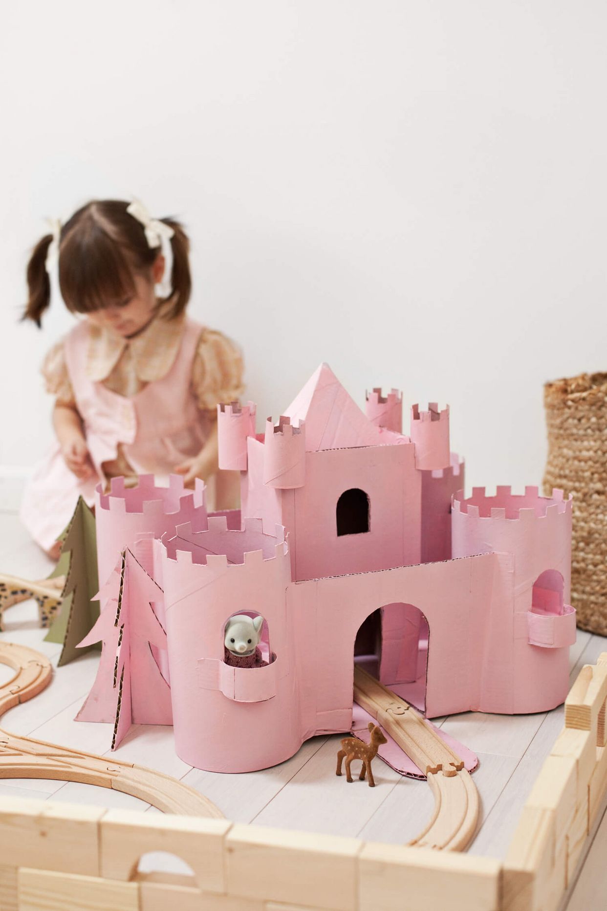 Holčička pri rúžovém hradě z kartonu