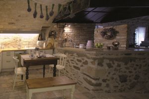Dřevěný vyřezávaný jídelní stůl, lavice i židle v starodávné kuchyni