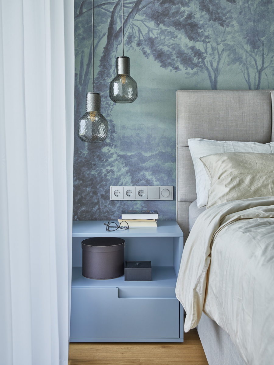Modrá ložnice s tapetou a dizajnovými svítidlami