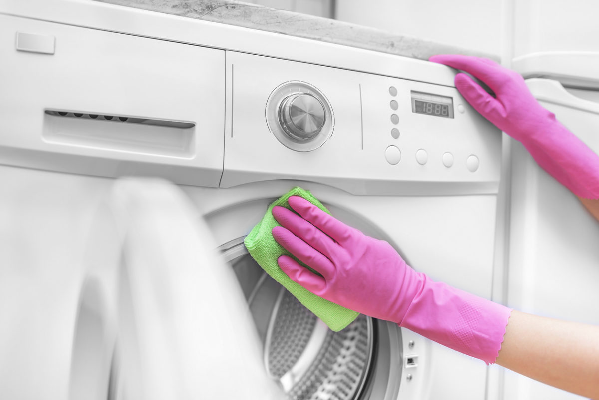 Žena čistí pračku v rukavicích