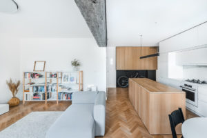 Svetlý obývák spojený s kuchyní s betonovým pilířem