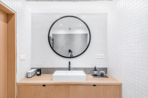 Bílá koupelna s betonóvým prvkem a dřevěným nábytkem