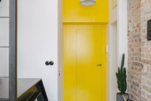 Žluté dveře v bílé chodbě