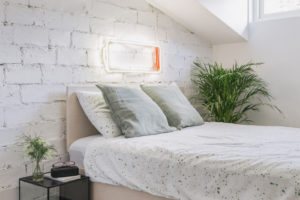 Utulná postel v podkroví s bílou cihlovou zdí