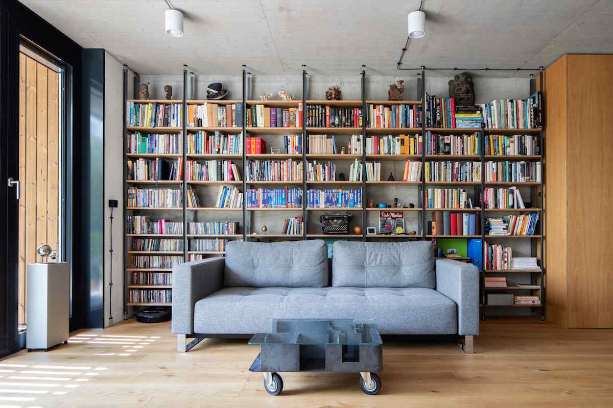 Velká knihovna se sivou pohovkou a dizajnovým skleněným stolkem