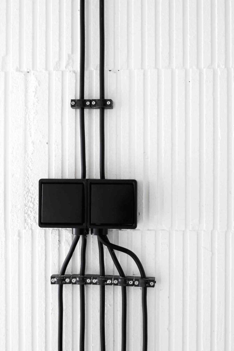 Bílá stěna s přiznaným elektrickým vedením v černé barvě