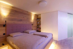 Pastelová ložnice s dřevěnou stěnou