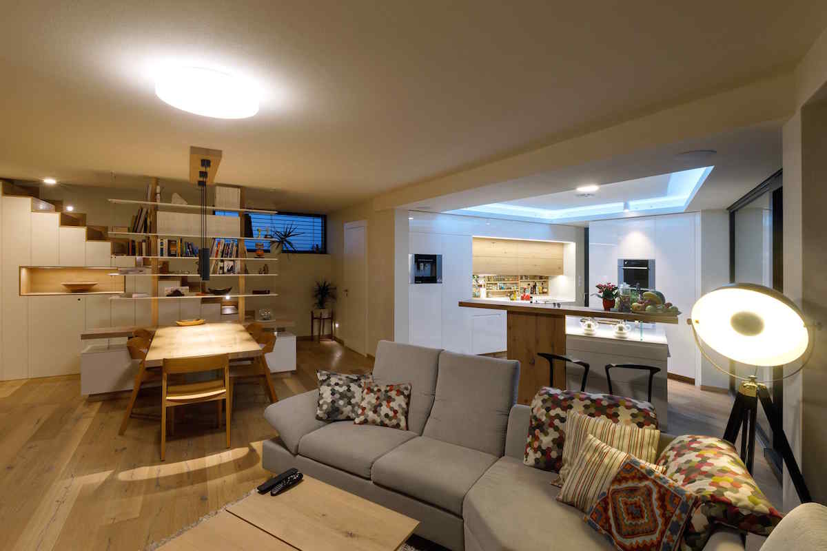 Otevřený prostor s bílou kuchyní a dřevěnou podlahou