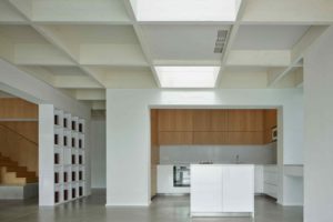Bílá kuchyň v otevřeném prostoru s kazetovým stropem