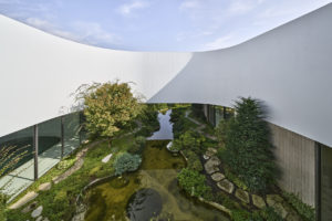 Atrium v bílé oblé vile s jezírkem a bohatou zahradou