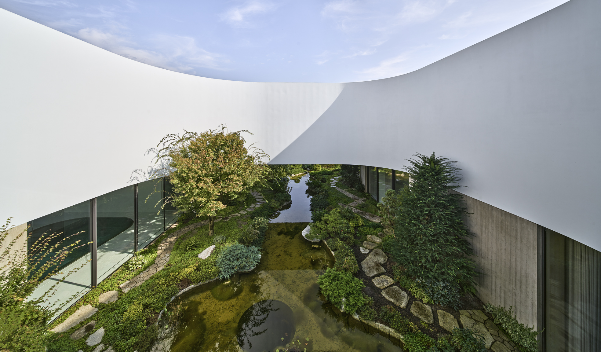 Atrium v bílé oblé vile s jezírkem a bohatou zahradou