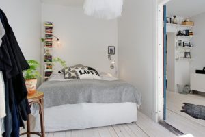 Jednoduchá ložnice s bílým lustrem a mini knihovničkou