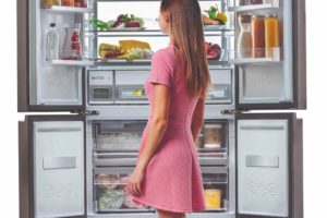 Otevřená americká chladnička a žena stojící před ní