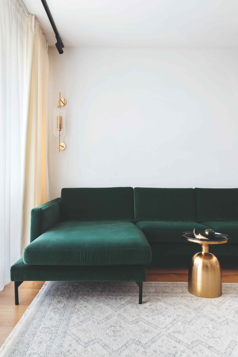 Smaragdově zelená pohovka a zlatý designový stolek