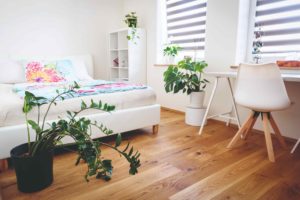 Bílá příjemná ložnice s dřevěnou podlahou