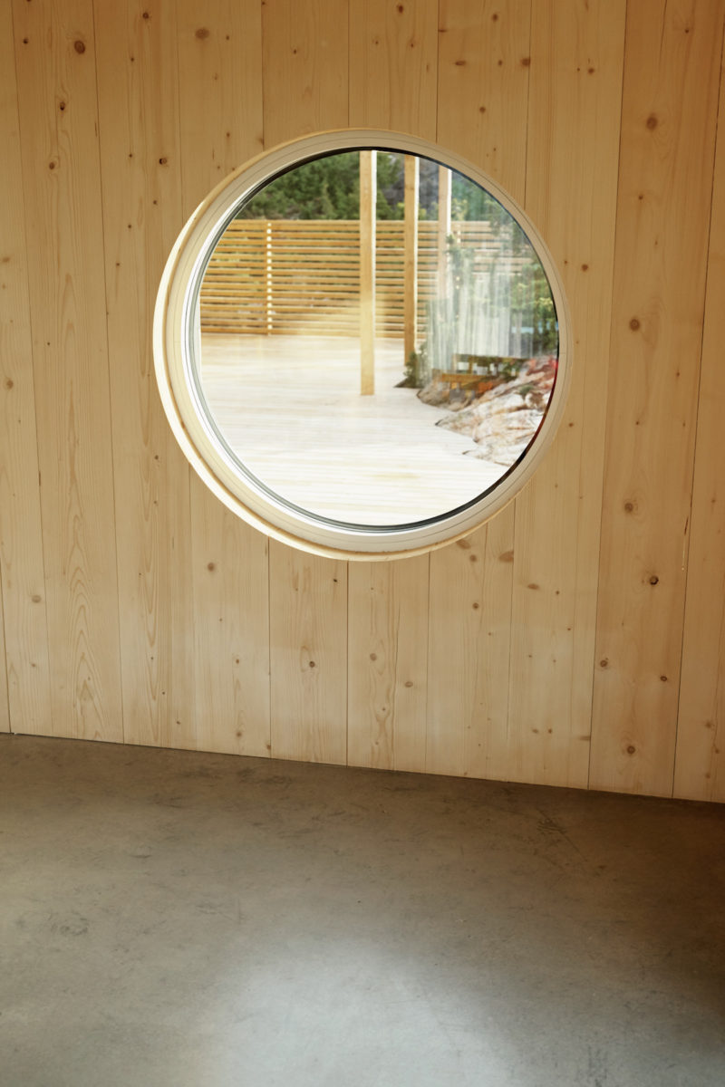 Neošetřené dřevěné stěny v interiéru s kulatým oknem