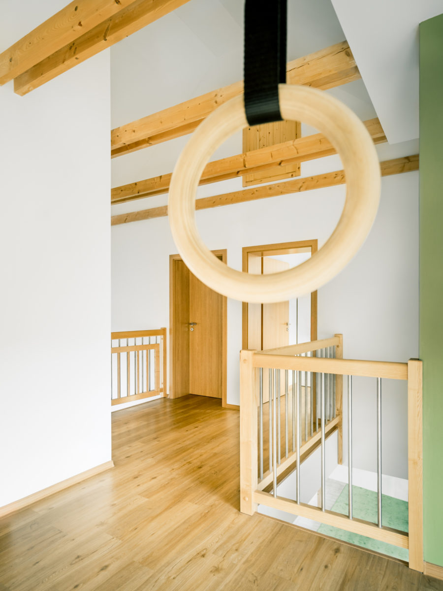 Otevřená galerie s dřevěnými odhalenými trámy a gymnastickými kruhy