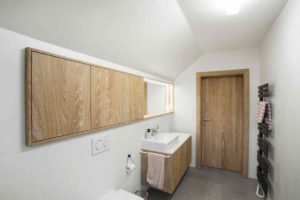 Bílá koupelna s dřevem a černým designovým radiátorem