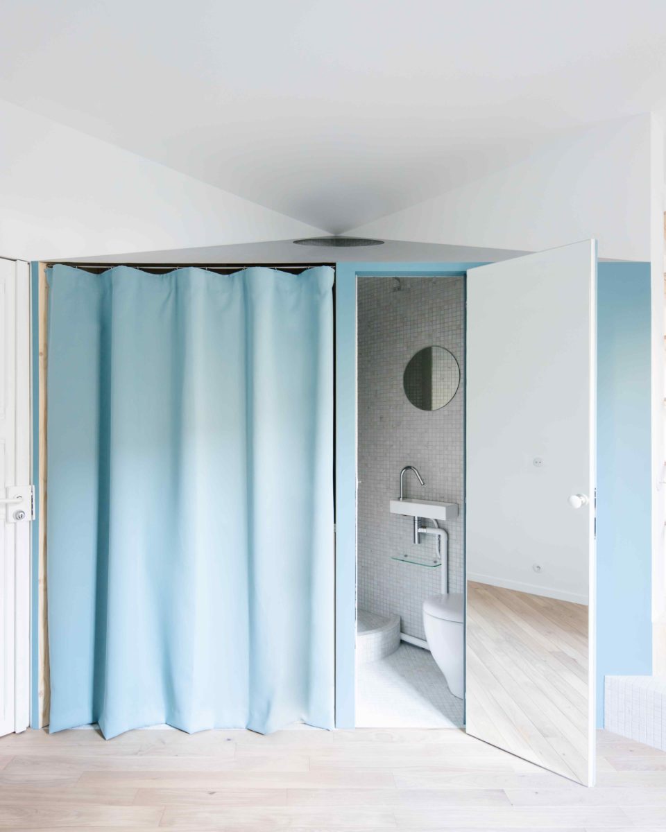 Modrý závěs v malém bytě se skrytou koupelnou