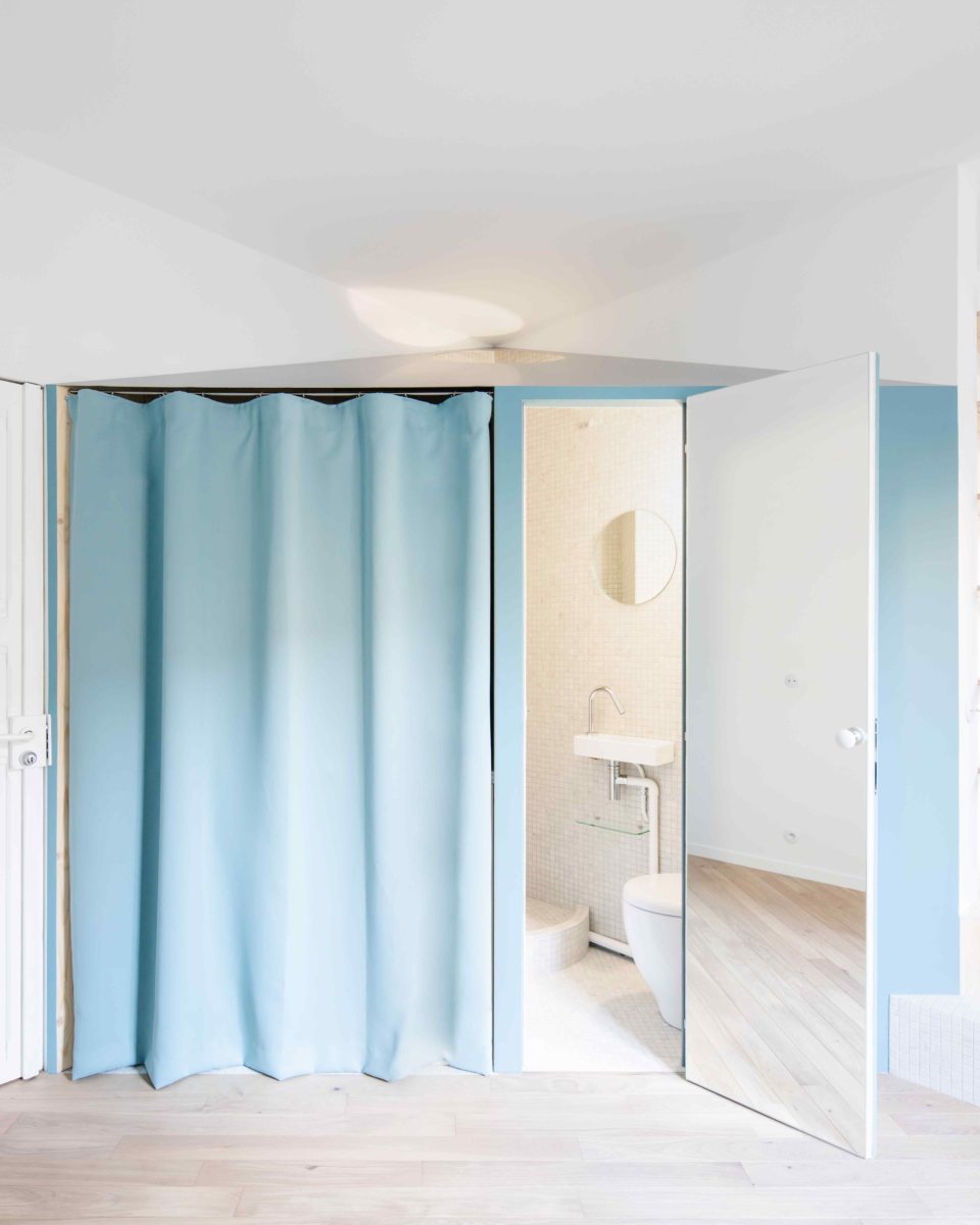 Modrý závěs v malém bytě se skrytou koupelnou