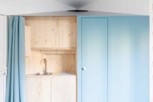 Modrý závěs v malém bytě se skrytou kuchynkou