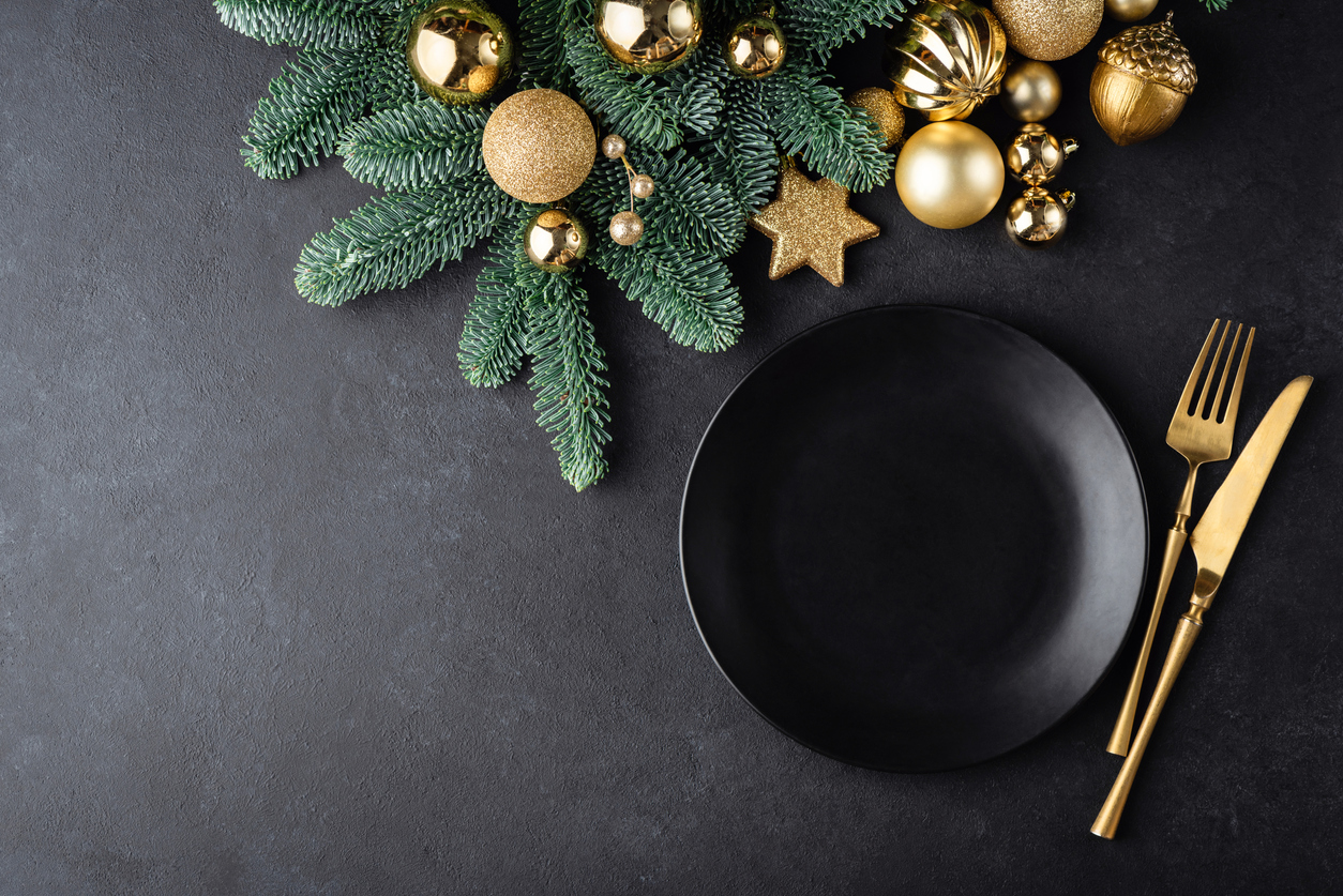 Christmas or New Year table setting with black plate and gold color cutlery