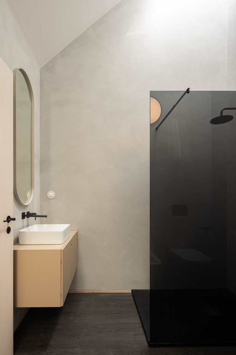 Béžová koupelna s oválným zrcadlem a černým koutem