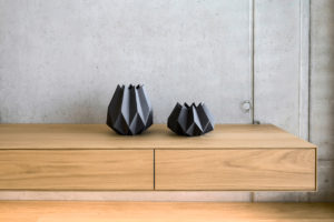Černé geometrické vázy na dřevěné skříňke