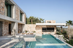 Středomořská vila s kamennou fasádou bazénem a prosklením