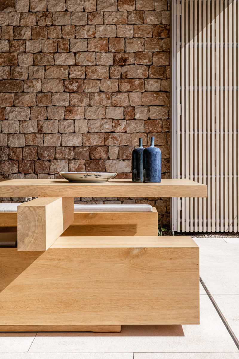 Jídelna ve středomořské vile s dřevěným stolem a kamennou zdí