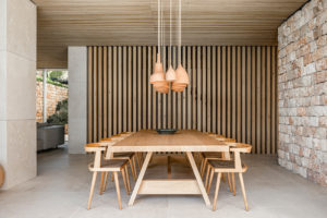 Jídelna ve středomořské vile s dřevěným stolem a designovými svítidli