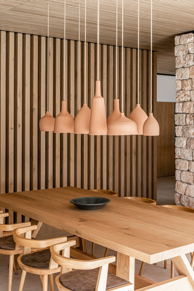 Jídelna ve středomořské vile s dřevěným stolem a designovými svítidli