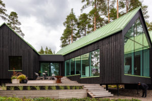 Hmoty tří budov z opalovaného dřeva se zelenou střechou