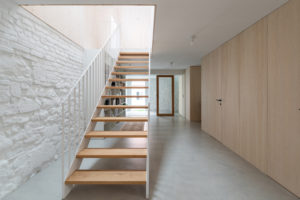 Schodiště v chodbě s dřevěnými obklady a bílou zdí