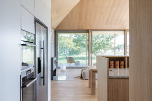 Dřevěná moderná kuchyň s výhledem cez prosklení do zahrady